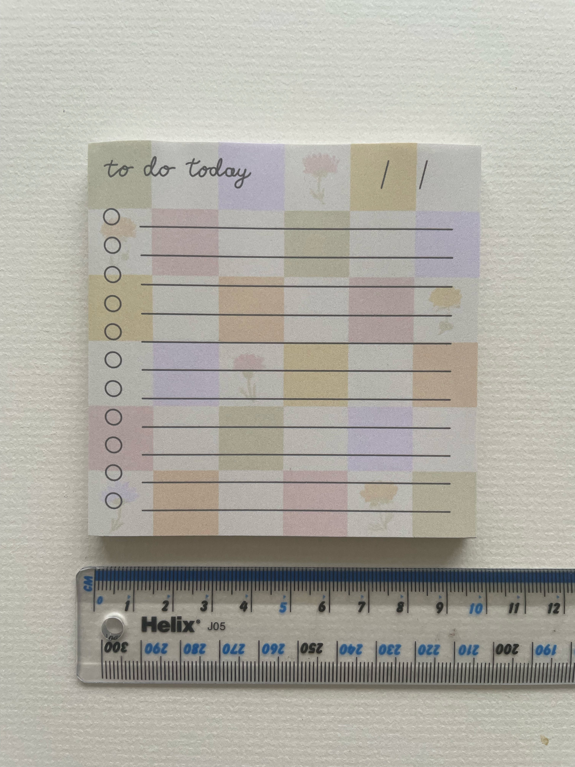 Small notepad with pastel color scheme and 'to do today' text next to a ruler on a white background