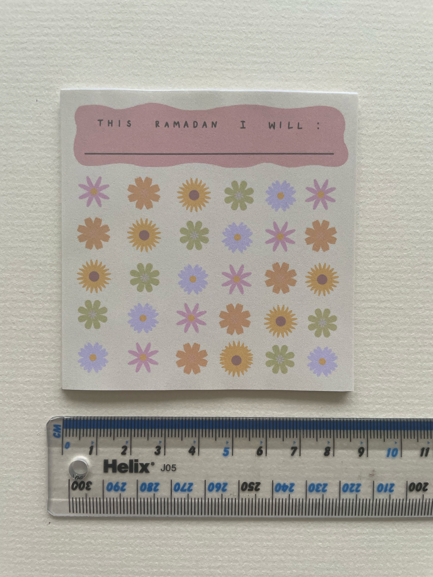 Notebook with floral stickers and a ruler for scale on a white background